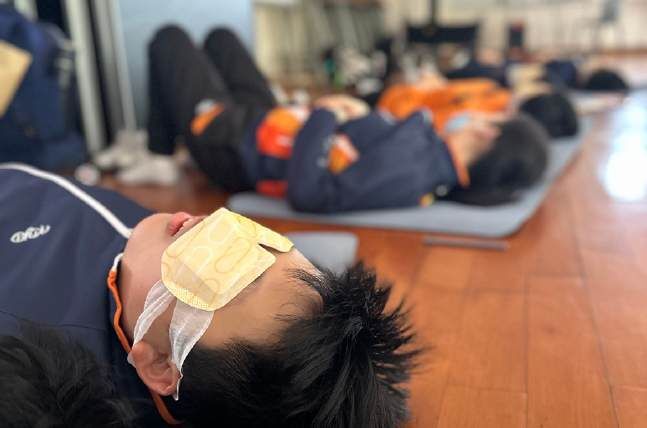 Students resting with eye pillows during a sound session