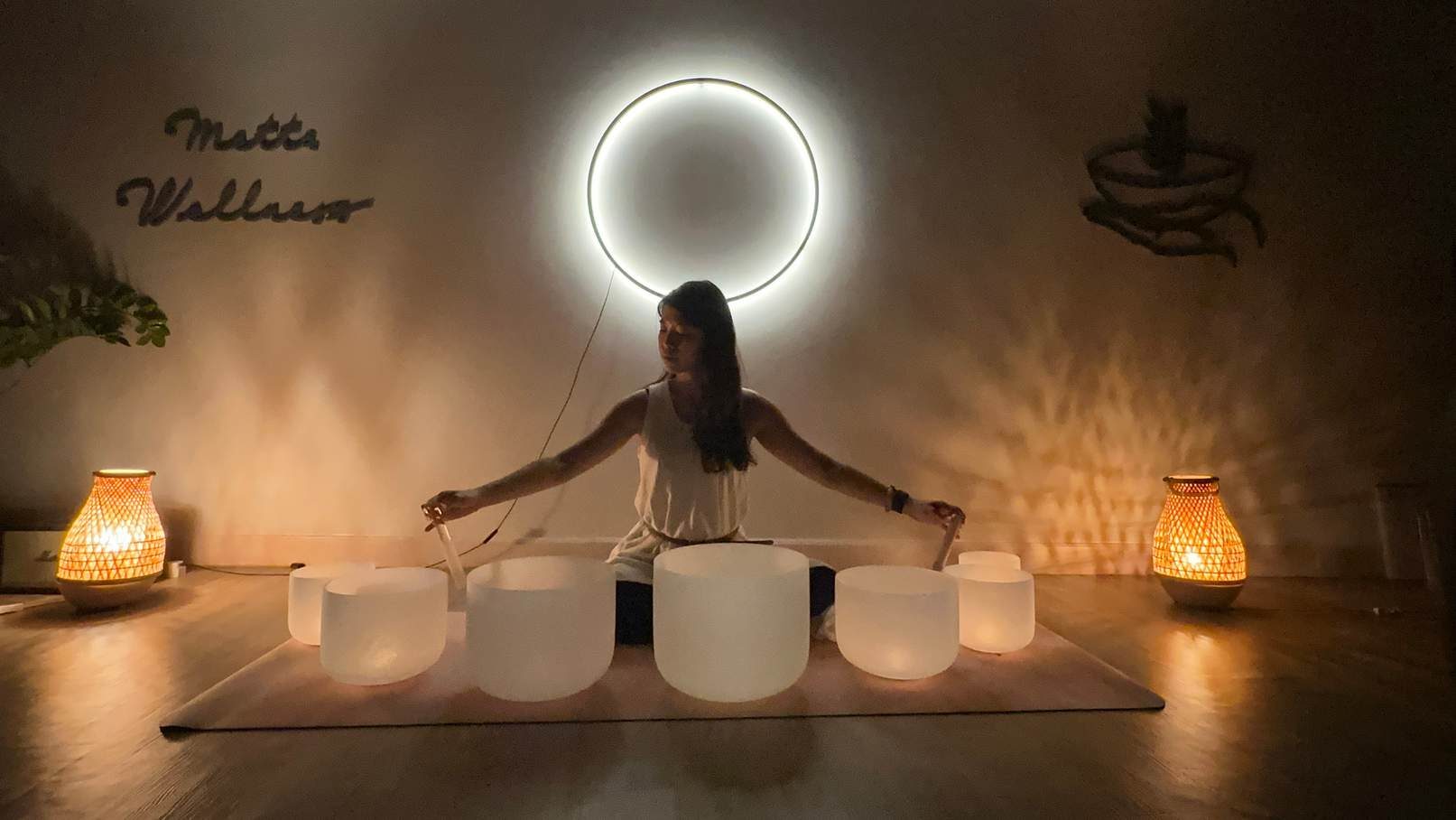 Helen Kwok playing frosted crystal singing bowls beneath a ring of light