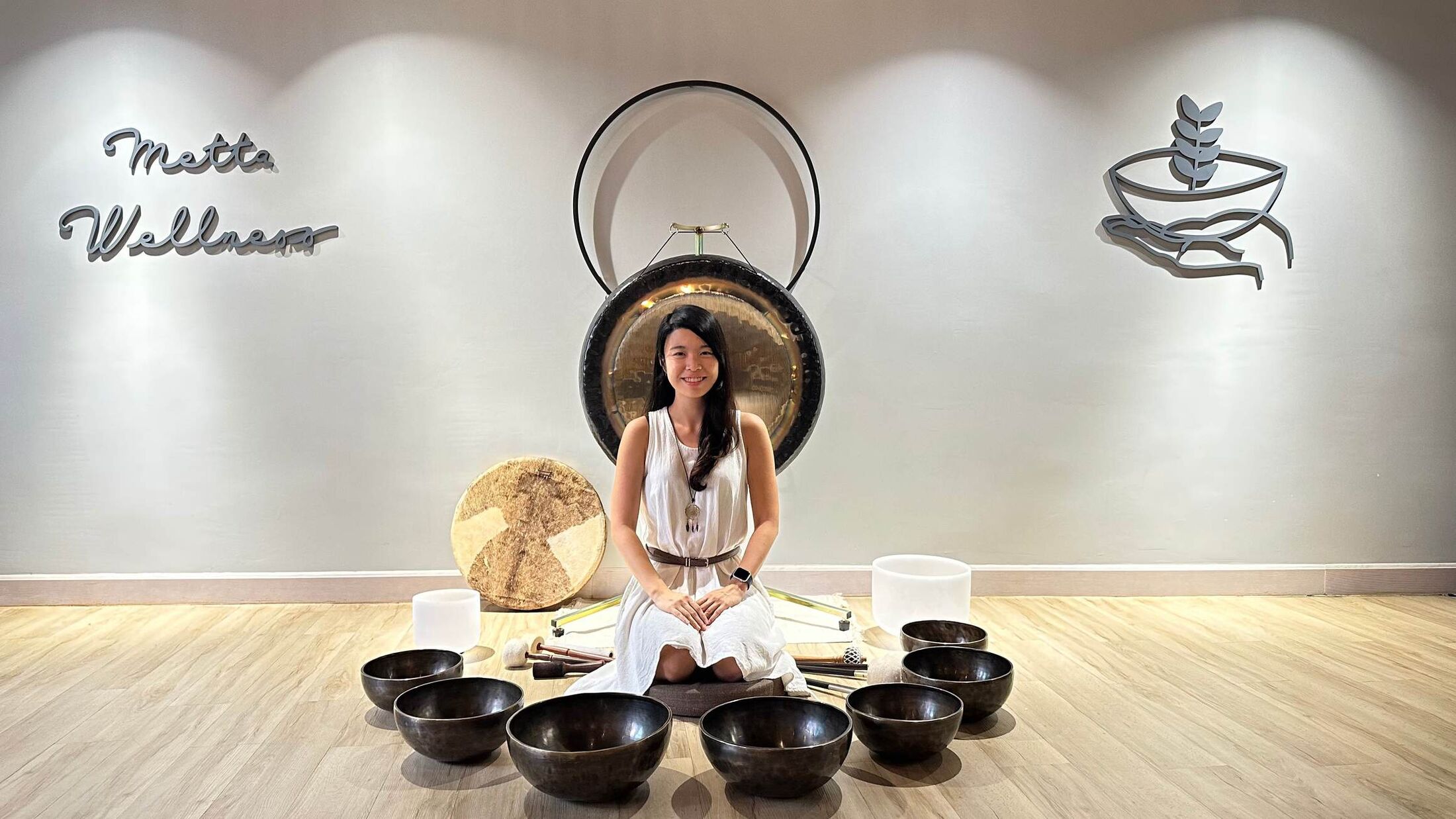 Helen seated before a gong among Tibetan singing bowls